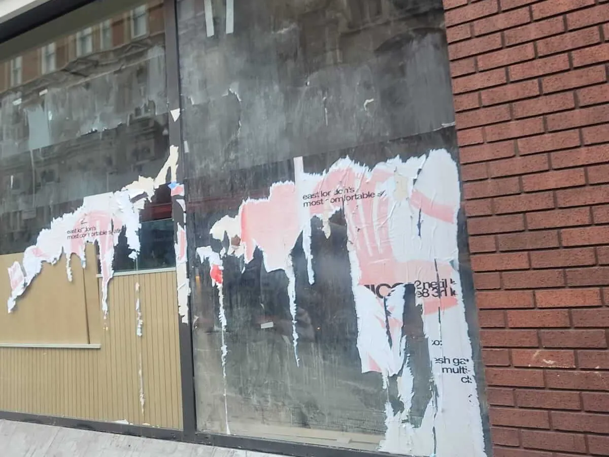 Amelia shopfront before cleaning: glass covered in torn posters and residue