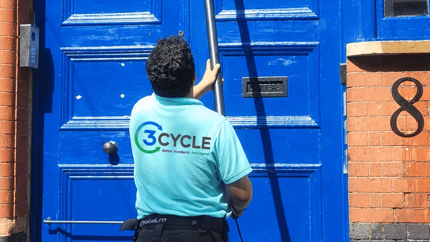 3Cycle window cleaner using a water-fed pole at a blue front door